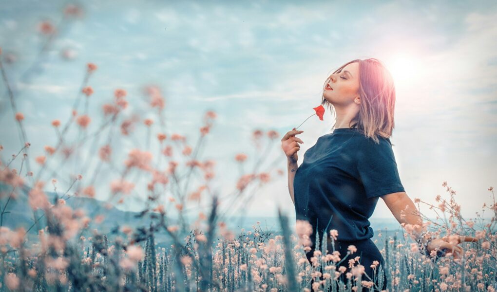 Jeune femme dans un champ de fleurs de couleurs rose .