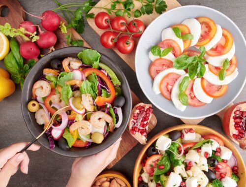 Personne en train de déguster des crevettes grillées et salade de légumes frais.