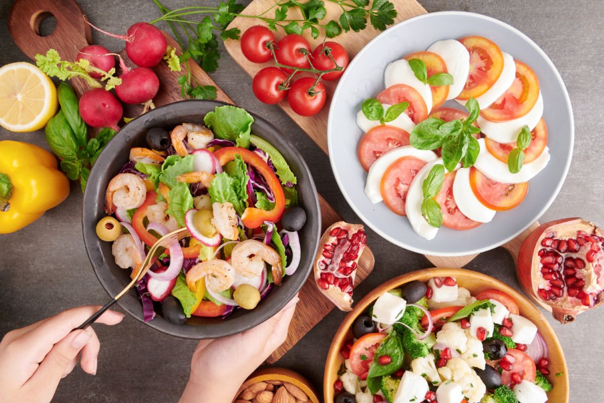 Personne en train de déguster des crevettes grillées et salade de légumes frais.