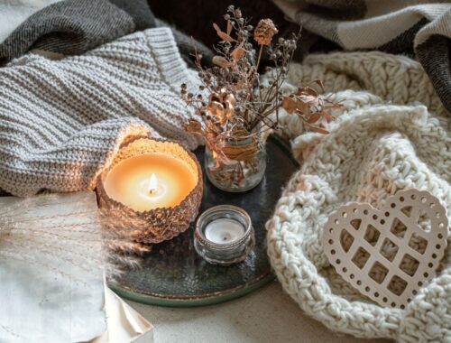 Nature morte avec des bougies dans des chandeliers, des détails de décoration et des articles de tricots