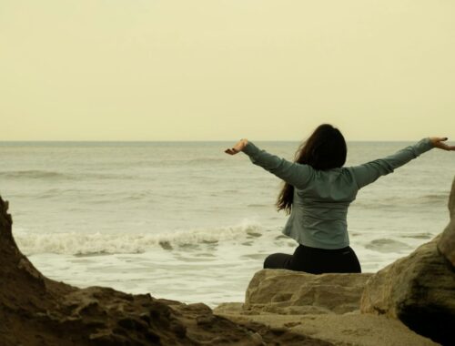 Femme les bras grands ouverts au coucher du soleil profitant d'un moment de sérenité.