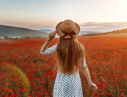 une jeune femme dans un champ de coquelicots au coucher du soleil