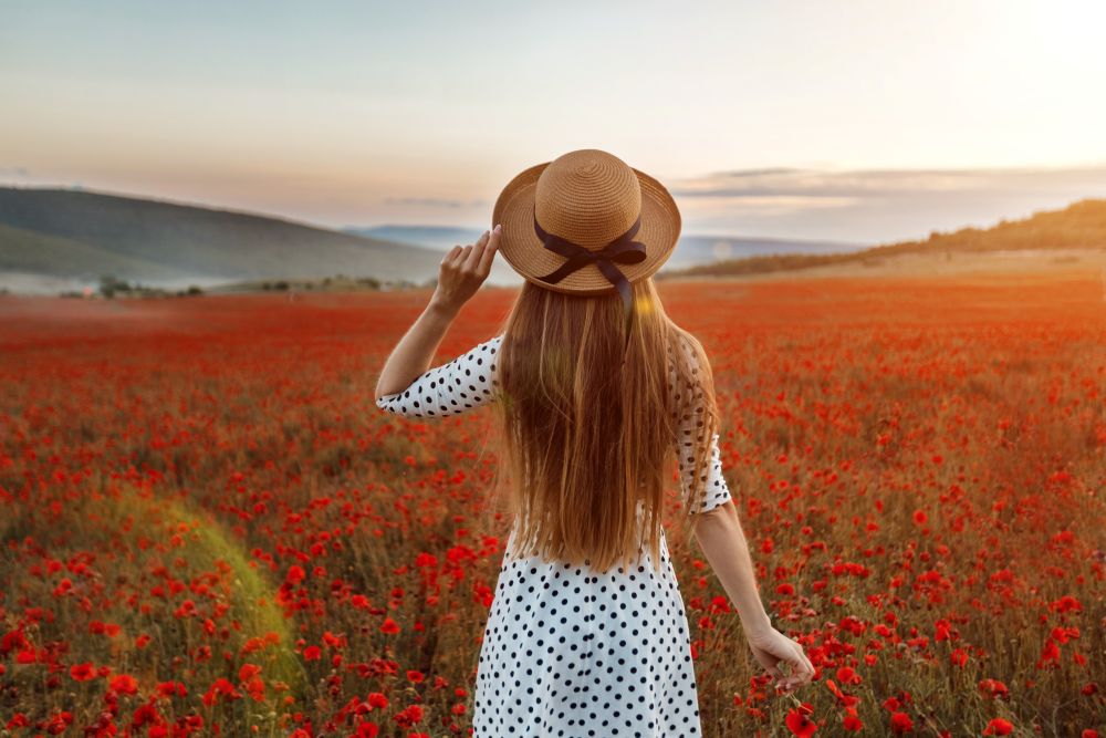 une jeune femme dans un champ de coquelicots au coucher du soleil